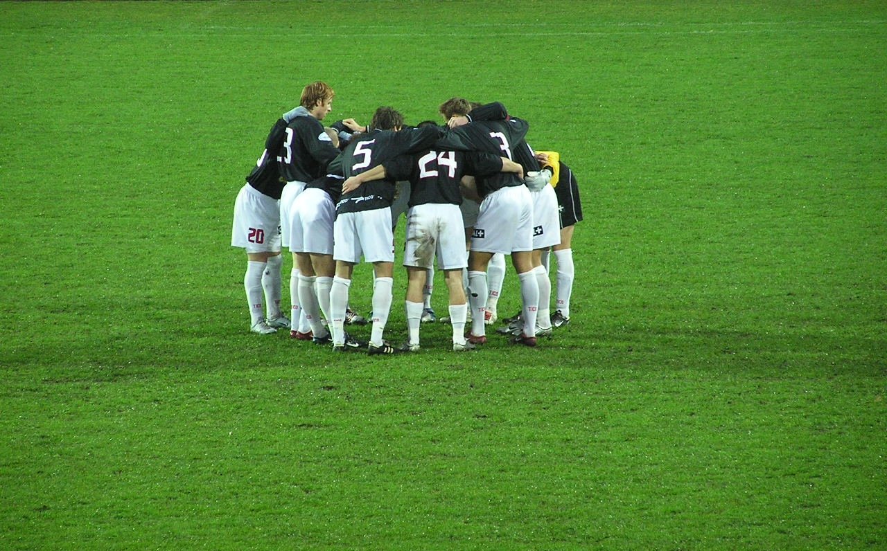 Football players standing in a circle on the pitch