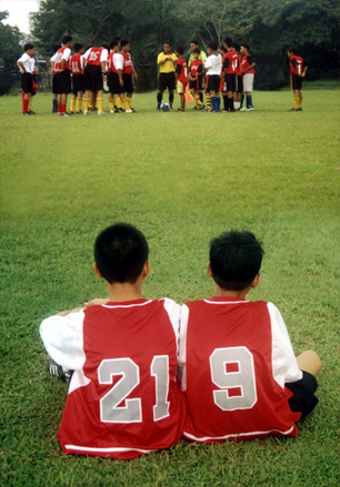 Two young football players sitting beside eachother